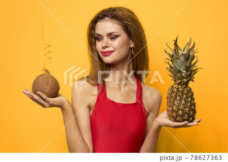 woman with coconut cocktail Pineapple in hands and critical fruits Red t-shirt yellow background woman with coconut cocktail Pineapple in hands and critical fruits Red t-shirt yellow background 78627363