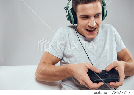 A man on the couch in front of a laptop with a joystick in a video game technology headphones 78627718