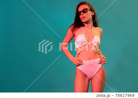 Woman in white swimsuit and sunglasses on blue background with copyspace 78627969