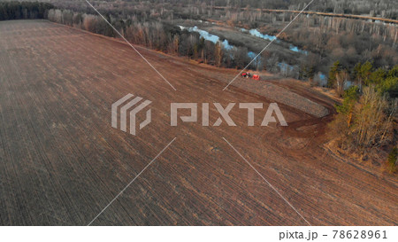 Aerial: tractor cultivates farmland near the river. Problem of freshwater pollution 78628961
