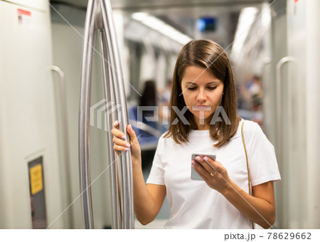 Female using mobile phone in subway car Female using mobile phone in subway car 78629662
