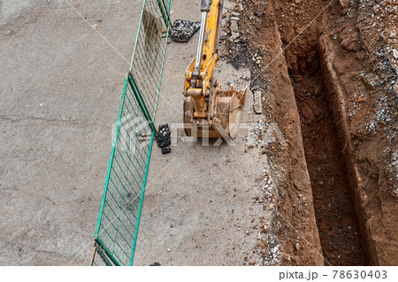 Excavator with bucket stands by deep pit change water pipes 78630403