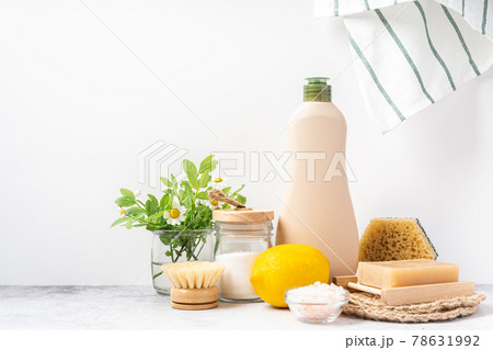 Eco friendly natural cleaners, jar with baking soda, dish brush, lemon, flowers, soap on white background. Organic ingredients for homemade cleans with mock up bottle. Zero waste concept, copy space 78631992