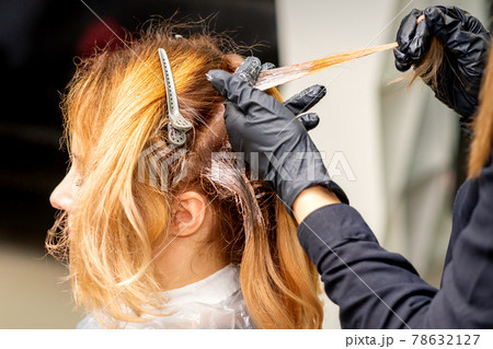 Hairdresser applying dye to strand of hair Hairdresser applying dye to strand of hair 78632127
