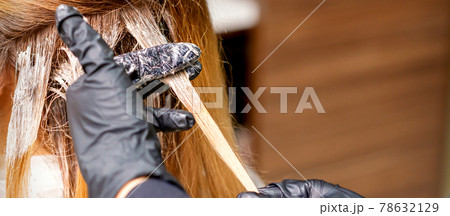 Hairdresser applying dye to strand of hair 78632129
