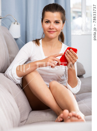 Young woman using smartphone on sofa at home interior 78633737