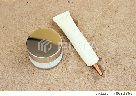 Cosmetic glass jar with white moisturizer and eye cream squeeze cosmetic tube with long nozzle and bronze screw cap on beach sand. Skincare sunscreen product set. Mockup, closeup. Cosmetic glass jar with white moisturizer and eye cream squeeze cosmetic tube with long nozzle and bronze screw cap on beach sand. Skincare sunscreen product set. Mockup, closeup. 78633866