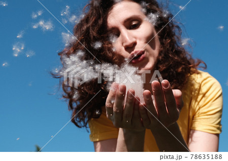 Girl blows poplar fluff off her hands. Fluff flies in different directions 78635188