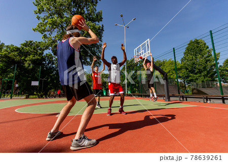 Group of young multiracial basketball players having friendly game at outdoor arena, free space Group of young multiracial basketball players having friendly game at outdoor arena, free space 78639261