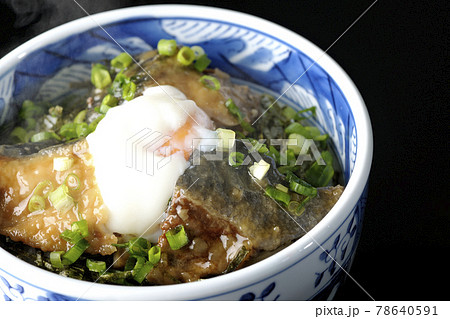 温玉とたっぷりの小ねぎがトッピングされた熱々鰤の照り焼き丼を黒背景で撮影 78640591