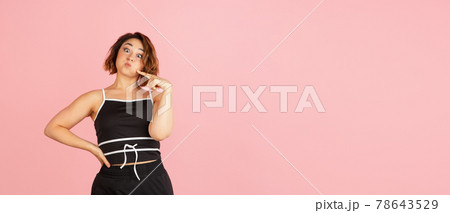 One young Caucasian beautiful woman in black white attire isolated on light pink background. One young Caucasian beautiful woman in black white attire isolated on light pink background. 78643529