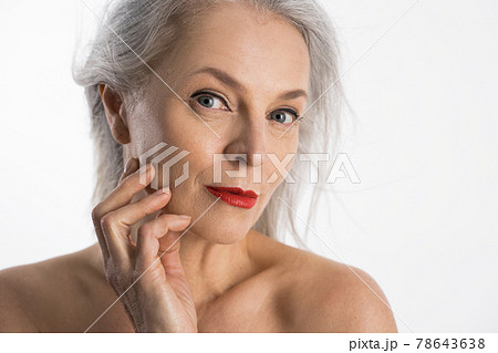 Woman with red lips looking to the camera with light smile and touching her cheek Woman with red lips looking to the camera with light smile and touching her cheek 78643638