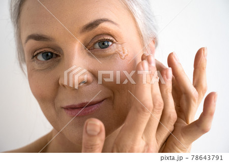 Female person pipetting rejuvenation oil on face with her hands Female person pipetting rejuvenation oil on face with her hands 78643791