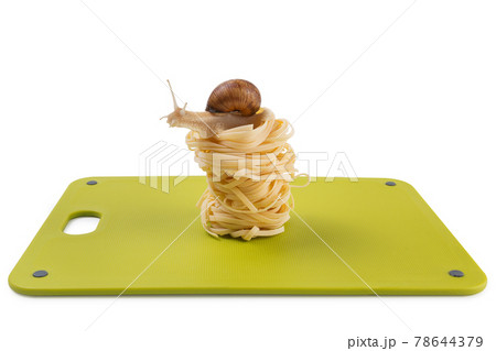 nests of noodles are stacked on a green cutting board, a snail sits on the top, concept, on a white background 78644379