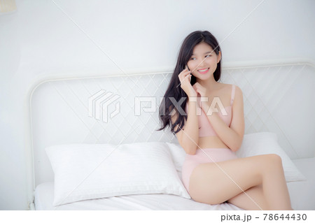 Beautiful young asian woman sexy in underwear happy talking on smartphone on bed. 78644430