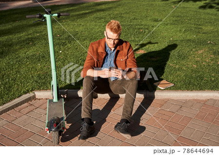 Male wearing glasses typing in mobile phone while looking at the gadget screen 78644694