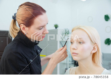 Process of making makeup. Make-up artist working with brush on model face. 78645358
