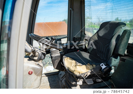 Old empty shabby driver's seat in cab of tractor, crane at a farm 78645742