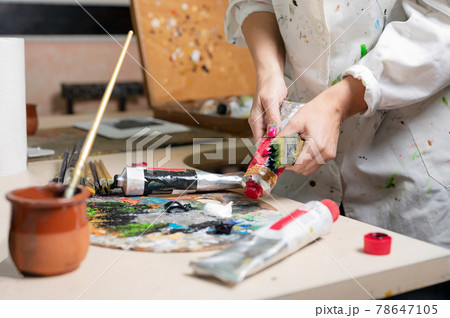 Creative female painter mixes palette of oil paints in palette. Close-up view Creative female painter mixes palette of oil paints in palette. Close-up view 78647105