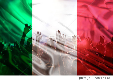football fans supporting Italy - crowd celebrating in stadium with raised hands against Italy flag 78647438