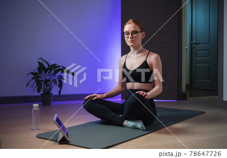 An experienced yoga coach conducts an online yoga class, the girl shows her students how to properly sit in the lotus position for meditation 78647726
