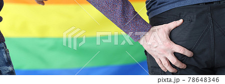 Man's hand rests on butt of another man against background of lgbt flag 78648346