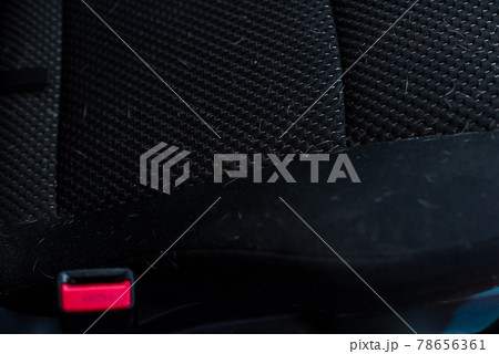 White dog hair on a black back seat of a car. 78656361