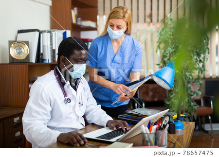 Male doctor and female in protective mask nurse having productive day Male doctor and female in protective mask nurse having productive day 78657475