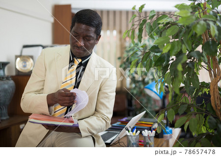 Concentrated african american businessman reading papers in office Concentrated african american businessman reading papers in office 78657478