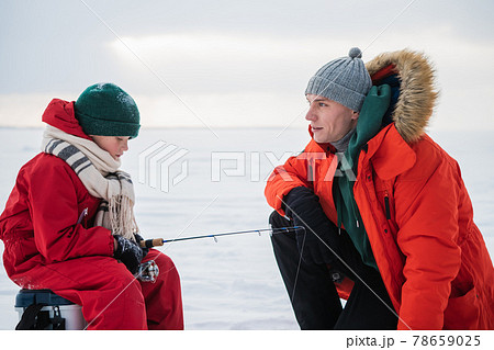 Father and son in red winter clothes came to fish on the river bank in winter Father and son in red winter clothes came to fish on the river bank in winter 78659025