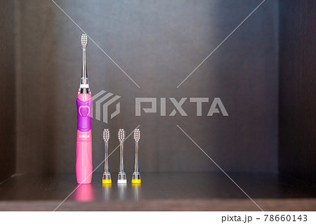 Children's electric pink toothbrush with backlight with three interchangeable nozzles stands on a shelf 78660143