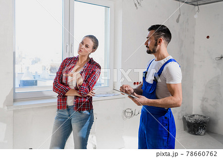 The client talks to the craftsman in overalls. He writes in a notebook 78660762
