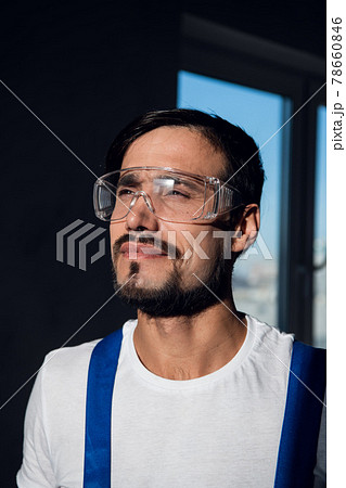 Builder in blue overalls, white shirt and goggles 78660846