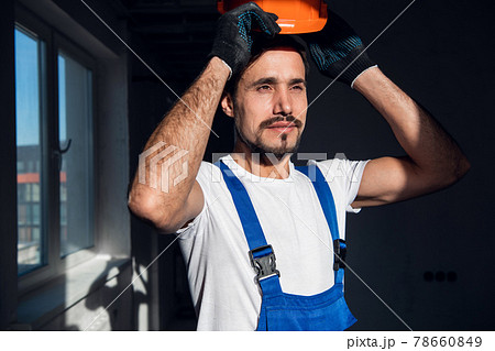 Young architect puts orange hard hat on his head 78660849