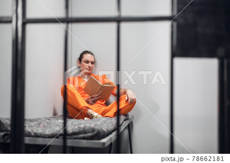 A young inmate with a tattooed face is being remotely trained in a cell. Reads a textbook sitting on a bunk. A young inmate with a tattooed face is being remotely trained in a cell. Reads a textbook sitting on a bunk. 78662181