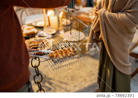 People serving grilled sausages on a table outdoors People serving grilled sausages on a table outdoors 78662301
