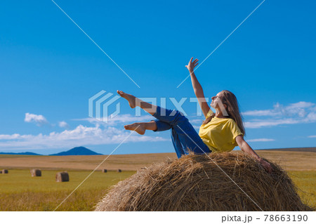 a girl is sunbathing in the hay. village life: harvesting hay for the winter. animal feed. a girl is sunbathing in the hay. village life: harvesting hay for the winter. animal feed. 78663190