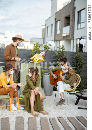 Friends in face mask celebrating outdoors 78663556