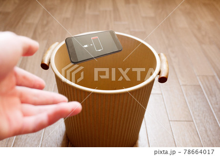 バッテリーの劣化したスマートフォンをゴミ箱に投げ捨てる 78664017