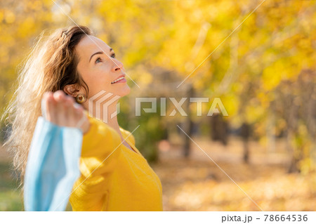 Happy woman wearing protective mask in autumn park Happy woman wearing protective mask in autumn park 78664536