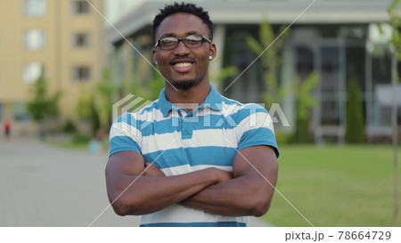 Portrait of handsome young african american man in glasses laughing cheerful at camera enjoying sunny urban city. 78664729