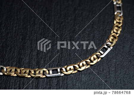 Gold and white chain on a stone board. 78664768