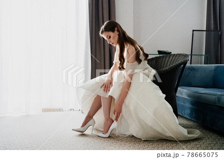 A beautiful bride puts on shoes. Preparing for the wedding ceremony. 78665075