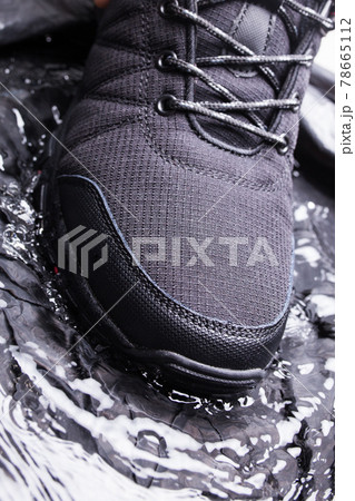 Black men's sneakers with drops of water, close-up on a black isolated background. 78665112