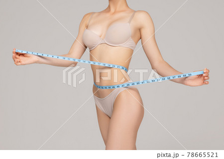 The girl taking measurements of her body, white background. 78665521