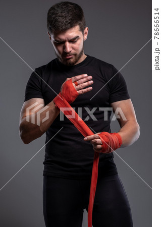 Focused young man wrapping hands with boxing tape 78666514