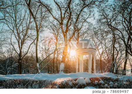 Gomel, Belarus. Winter City Park. Sun at sunset shining through gazebo in city park. Garden pergola in snow 78669497