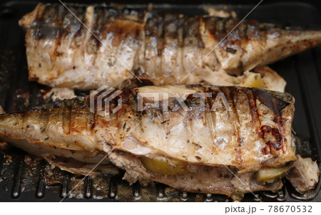 Mackerel is roasted on an electric grill. Grilled fish with lemon and salad Mackerel is roasted on an electric grill. Grilled fish with lemon and salad 78670532