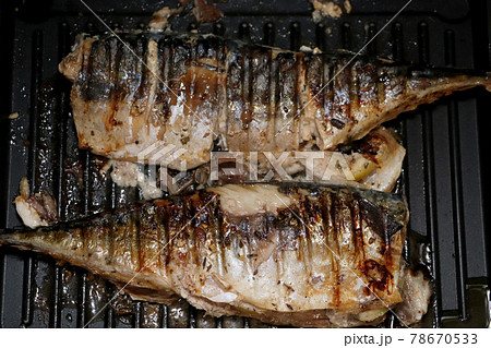 Mackerel is roasted on an electric grill. Grilled fish with lemon and salad Mackerel is roasted on an electric grill. Grilled fish with lemon and salad 78670533