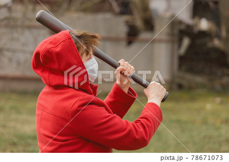 Angry aggressive elderly woman in protective safe medical mask swings baseball bat in the background of outdoor street, portrait, close up Angry aggressive elderly woman in protective safe medical mask swings baseball bat in the background of outdoor street, portrait, close up 78671073